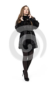 Young pretty girl posing in dark short mink fur coat, full height isolated on white background