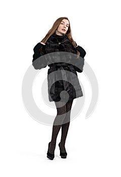 Young pretty girl posing in dark short mink fur coat, full height isolated on white background