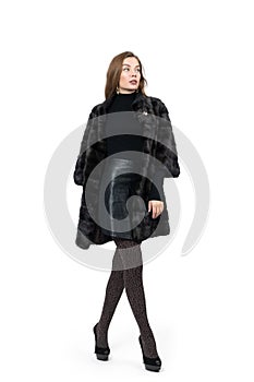 Young pretty girl posing in dark short mink fur coat, full height isolated on white background