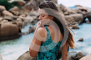 Young pretty girl posing in profile on the background of azure water in a birch fashionable swimsuit, gently touches her