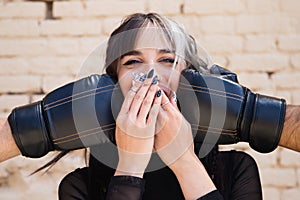 Young and pretty girl with a punkish tendency. She is being hit on each side of her face with boxing gloves while holding a jelly