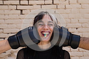 Young and pretty girl with a punkish tendency. She is being hit on each side of her face with boxing gloves while holding a jelly