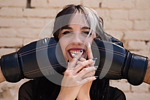 Young and pretty girl with a punkish tendency. She is being hit on each side of her face with boxing gloves while holding a jelly