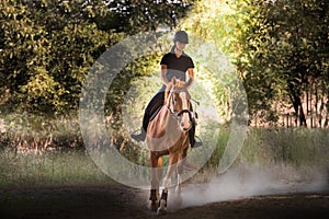 Young pretty girl riding a horse with backlit leaves behind