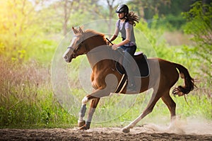 Young pretty girl riding a horse with backlit leaves behind in s