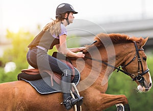 Young pretty girl riding a horse with backlit leaves behind in s