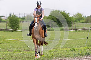 Young pretty girl riding a horse with backlit leaves behind in s