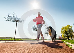 Young pretty girl running outdoor with her Bernese Mountain dog