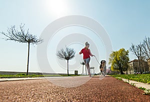 Young pretty girl running outdoor with her Bernese Mountain dog