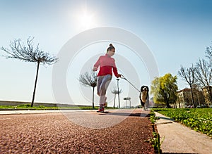 Young pretty girl running outdoor with her Bernese Mountain dog