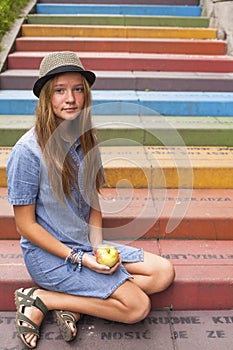 Young pretty girl sitting on the multicolored stone steps.