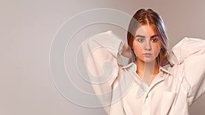 Young pretty girl straightens her long blond hair against white background