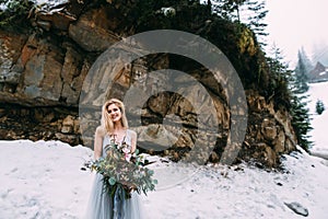 The young pretty girl waits for her lover in the middle of the mountains covered with snow