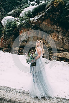 The young pretty girl waits for her lover in the middle of the mountains covered with snow