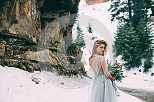 The young pretty girl waits for her lover in the middle of the mountains covered with snow
