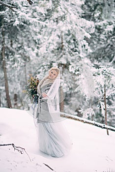 The young pretty girl waits for her lover in the middle of the mountains covered with snow