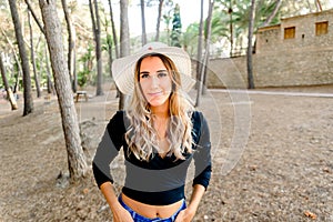 Young pretty girl walking through a park at sunset with jeans and hat, looking attractive