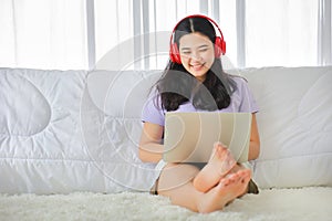 Young pretty girl watching movie from home on her bed using computer laptop to access media online