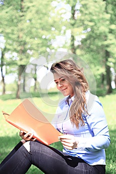 Young pretty girl working on laptop outdoor, lying on grass, caucasian 20 years old