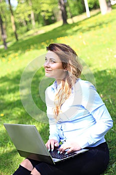 Young pretty girl working on laptop outdoor, lying on grass, caucasian 20 years old