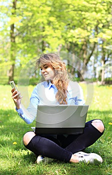 Young pretty girl working on laptop outdoor, lying on grass, caucasian 20 years old