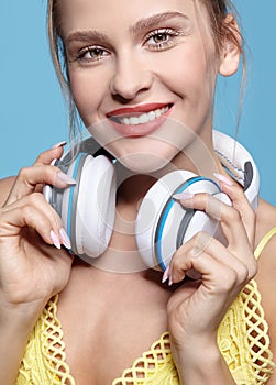 Young pretty happy woman in yellow dress listening to music in headphones