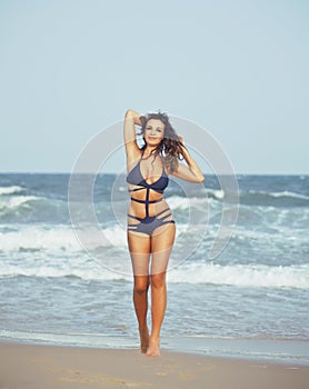 Young pretty hispanic woman on seacoast with flying hair, hot se