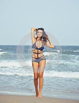 Young pretty hispanic woman on seacoast with flying hair, hot se