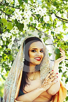 Young pretty indian girl in jewelry and veil posing cheerful happy smiling in green park, lifestyle people concept