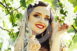 Young pretty indian girl in jewelry and veil posing cheerful happy smiling in green park, lifestyle people concept