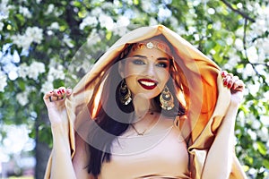 Young pretty indian girl in jewelry and veil posing cheerful happy smiling in green park, lifestyle people concept