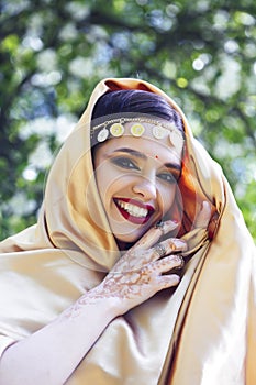 Young pretty indian girl in jewelry and veil posing cheerful happy smiling in green park, lifestyle people concept