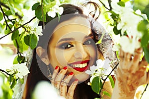 Young pretty indian girl in jewelry and veil posing cheerful happy smiling in green park, lifestyle people concept