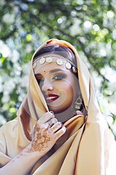 Young pretty indian girl in jewelry and veil posing cheerful happy smiling in green park, lifestyle people concept