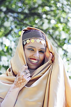 Young pretty indian girl in jewelry and veil posing cheerful happy smiling in green park, lifestyle people concept