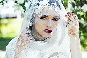 Young pretty indian girl in jewelry and veil posing cheerful happy smiling in green park, lifestyle people concept