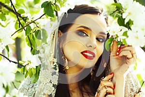 Young pretty indian girl in jewelry and veil posing cheerful happy smiling in green park, lifestyle people concept