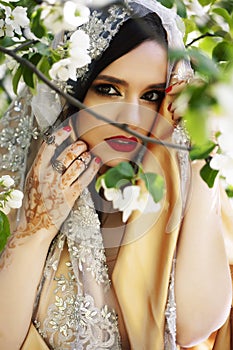 Young pretty indian girl in jewelry and veil posing cheerful happy smiling in green park, lifestyle people concept