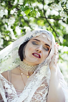 Young pretty indian girl in jewelry and veil posing cheerful happy smiling in green park, lifestyle people concept