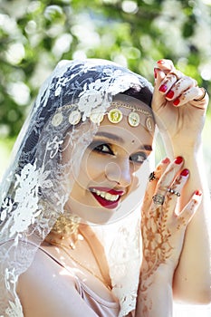 Young pretty indian girl in jewelry and veil posing cheerful happy smiling in green park, lifestyle people concept