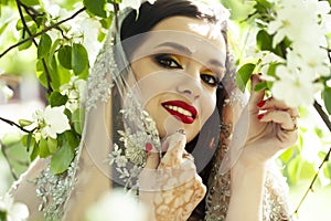 young pretty indian girl in jewelry and veil posing cheerful happy smiling in green park, lifestyle people concept