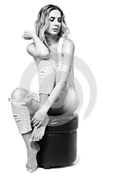 Young pretty in jeans and shirt woman sitting on pouffe stool