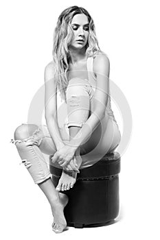 Young pretty in jeans and shirt woman sitting on pouffe stool