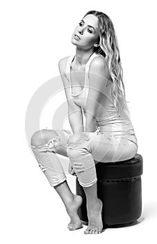 Young pretty in jeans and shirt woman sitting on pouffe stool