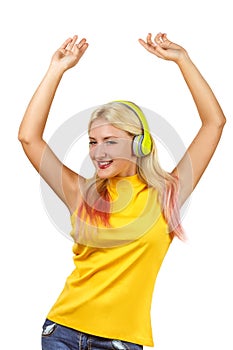 Young pretty joyful girl in yellow sleeveless shirt is dancing in yellow earphones