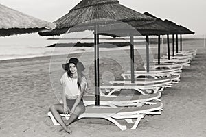 Young pretty lady on beach relaxing in the evening on chair lounge, summer outdoors background