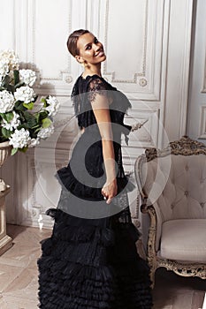 young pretty lady in black lace fashion style dress posing in rich interior of royal hotel room, luxury lifestyle people
