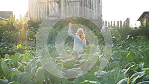 Young pretty lady in cap walks along green garden plants