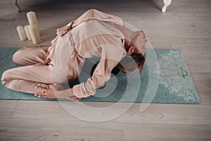 Young pretty lady doing asana at home on yoga mat