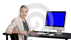 Young pretty lady talking to the camera and showing something on the screen of the computer, white background. Blue